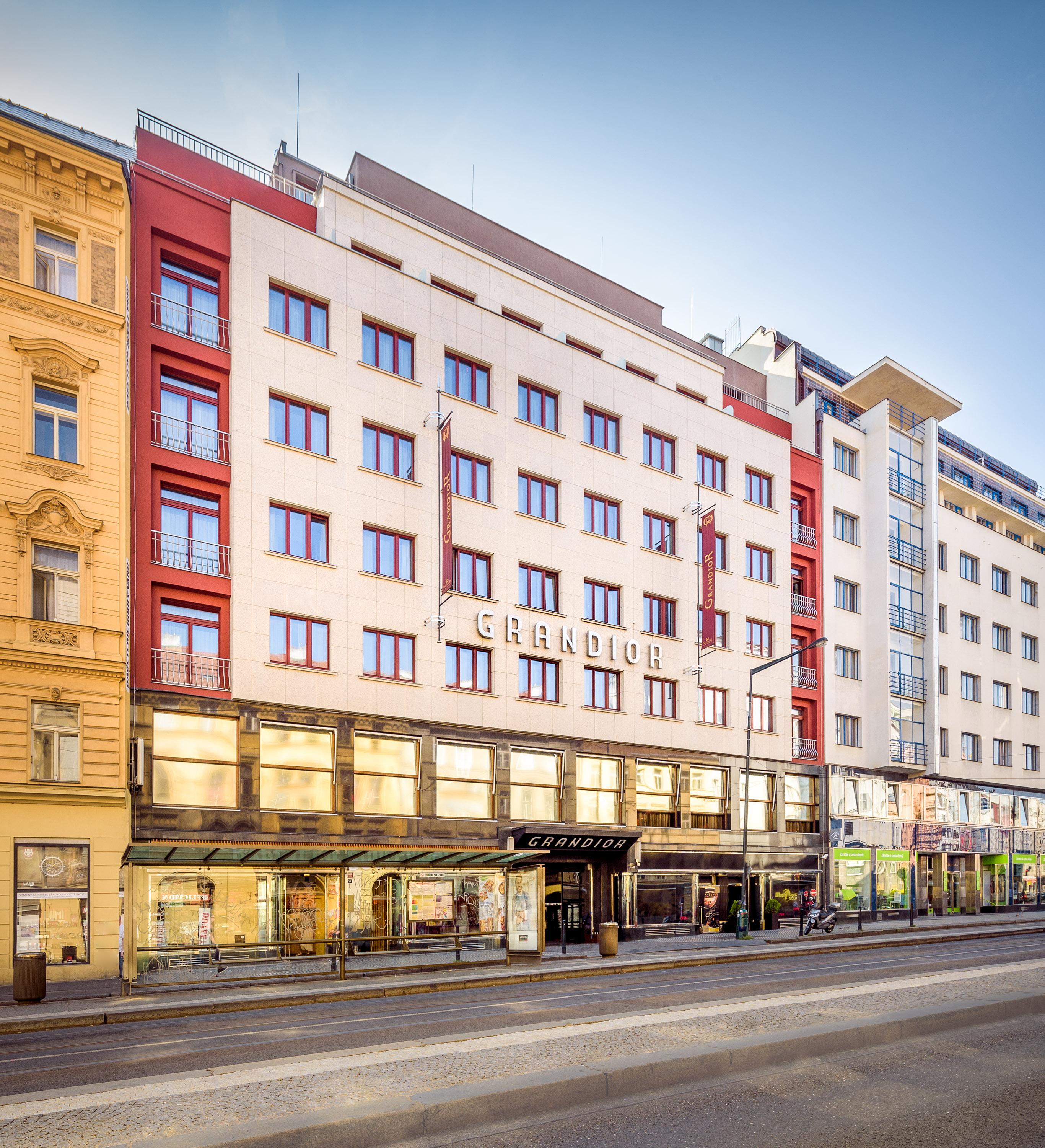 Grandior Hotel Praga Esterno foto The photo shows a multi-story building featuring a modern architectural design, with a prominent sign displaying "GERARD" on the facade. The building has a mix of colored panels, with white, red, and gray elements. Large windows are present on the up
